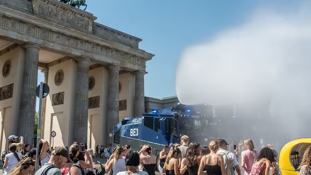 Polizei-Wasserwerfer besprüht bei Hitze eine Menschenmenge am Brandenburger Tor in Berlin